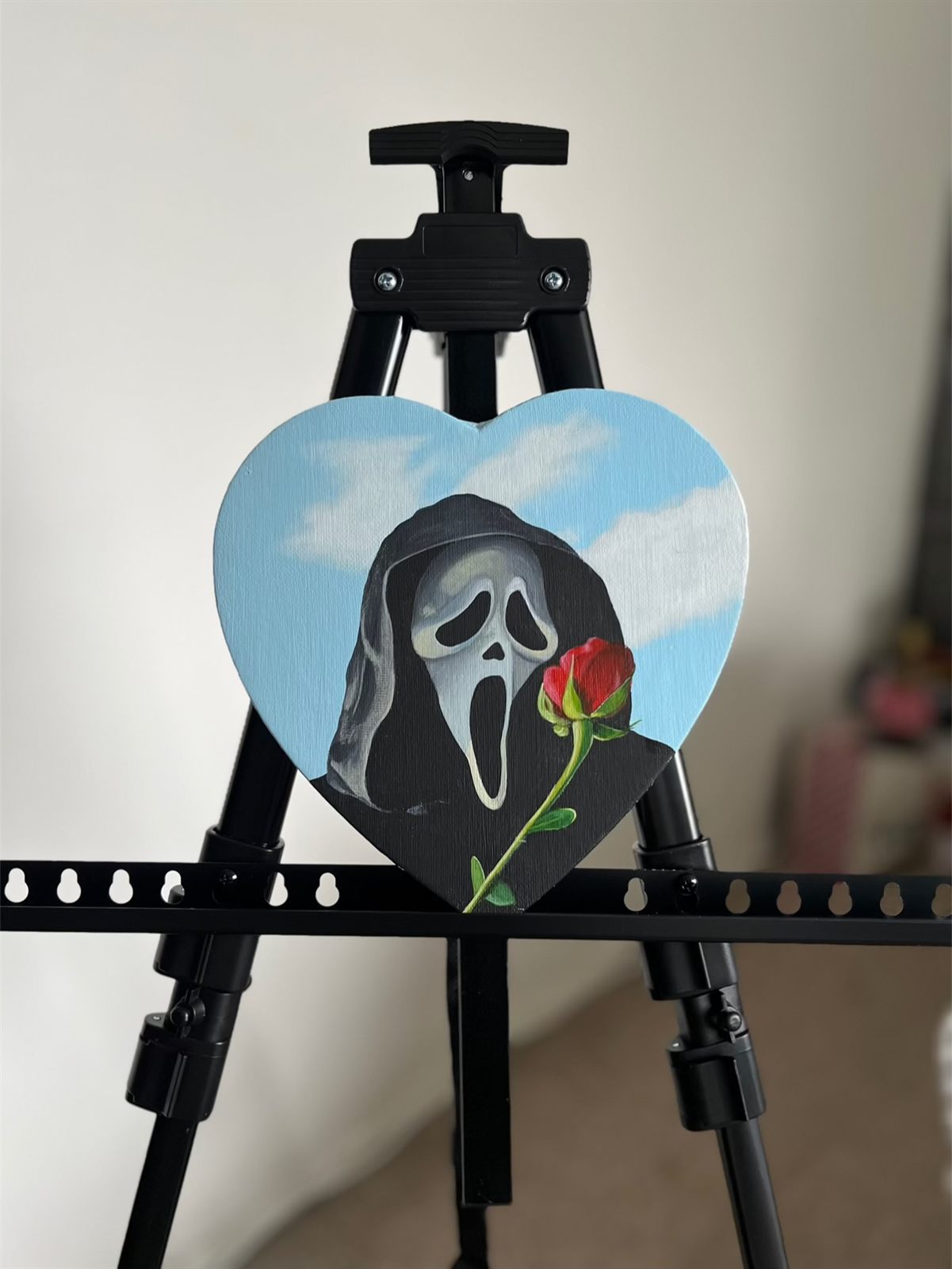 The Ghostface canvas standing on a black easel indoors