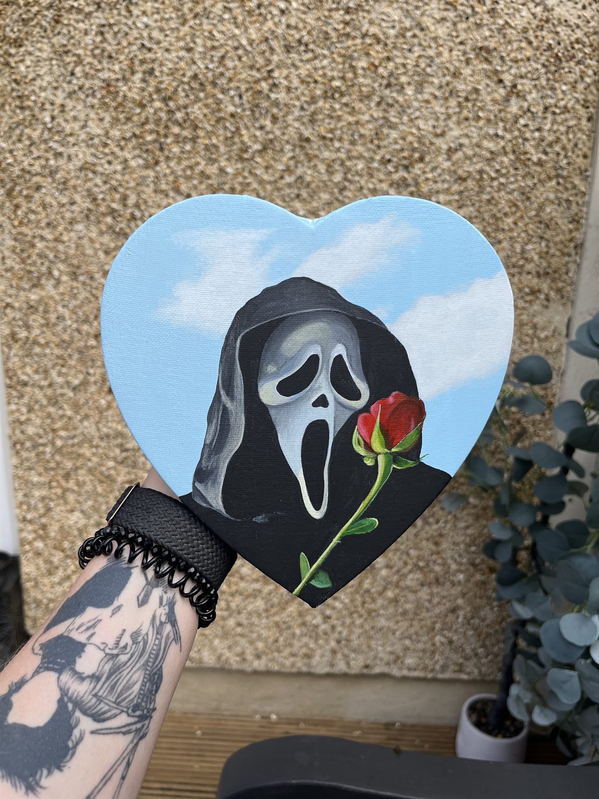 Ghostface held in one hand outdoors, showing the size of the heart-shaped canvas