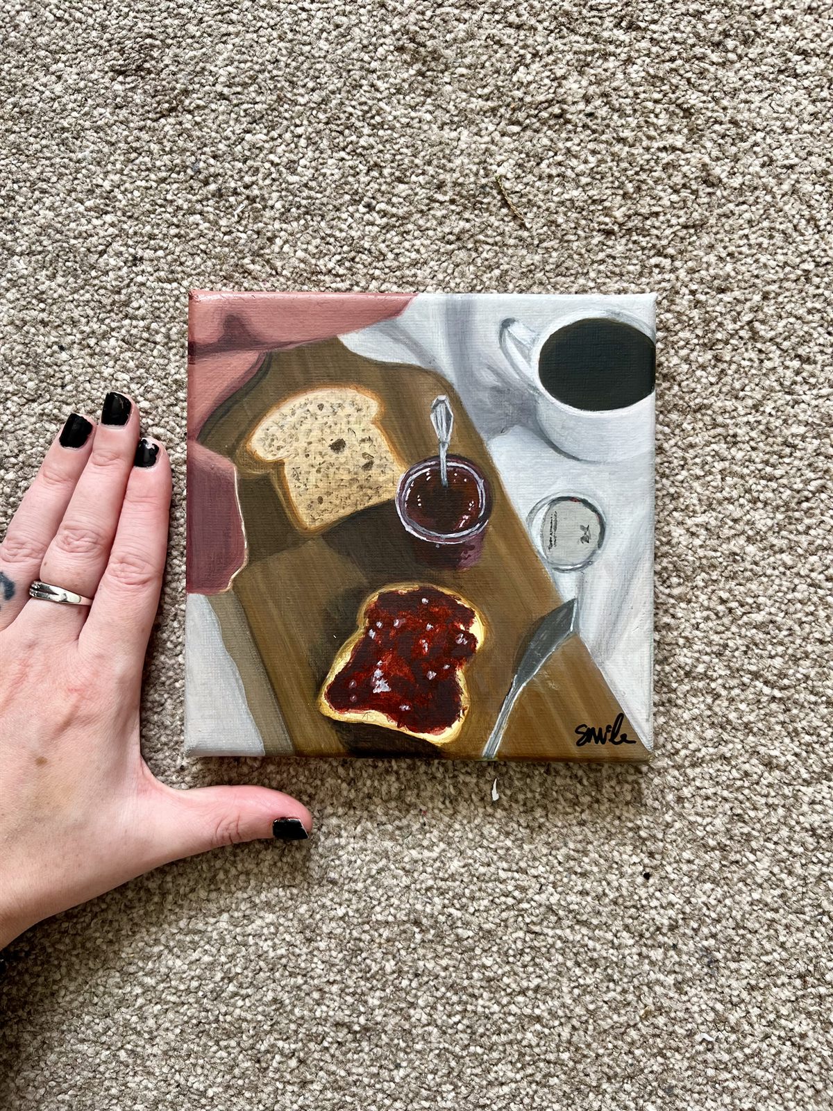 The Strawberry Jam canvas beside a hand, showing how small the six inch square canvas is